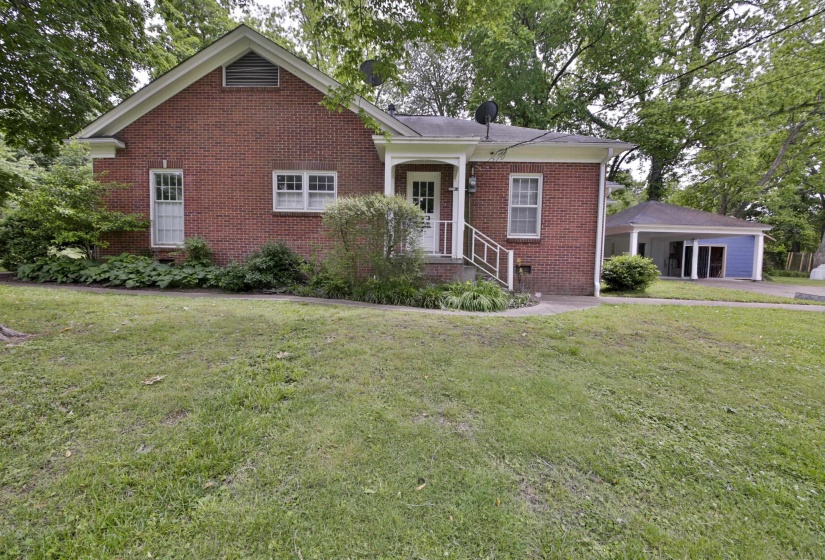 Brick exterior with white trim, featuring a front porch with white railing and a covered carport with white columns