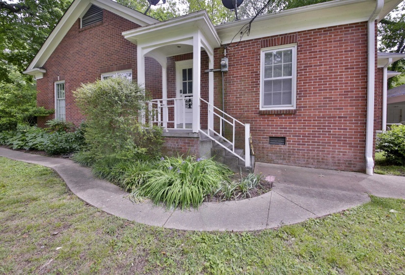 Brick exterior featuring a covered entry porch with white columns and railings