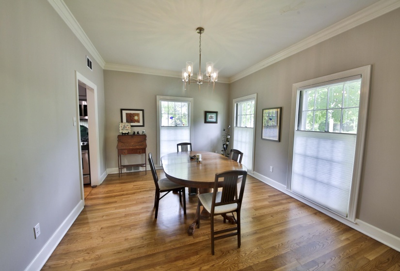 Dining area featuring wood-finish flooring, neutral wall tones, and crown molding