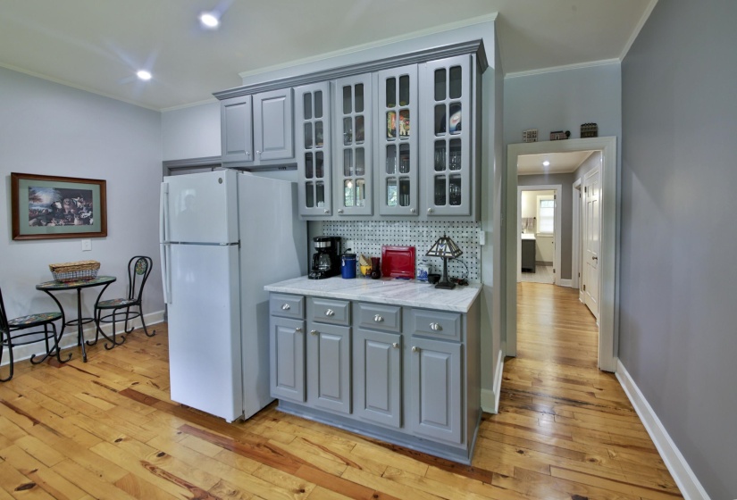 Kitchenette featuring wood-finish flooring, white refrigerator, gray cabinetry with glass-front uppers, and a light-toned countertop