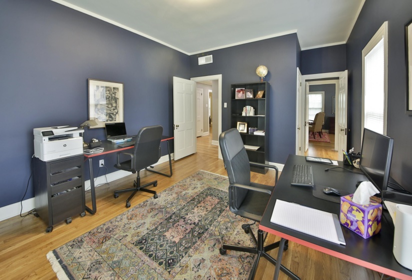 Interior room featuring hardwood flooring, crown molding, and two white doors
