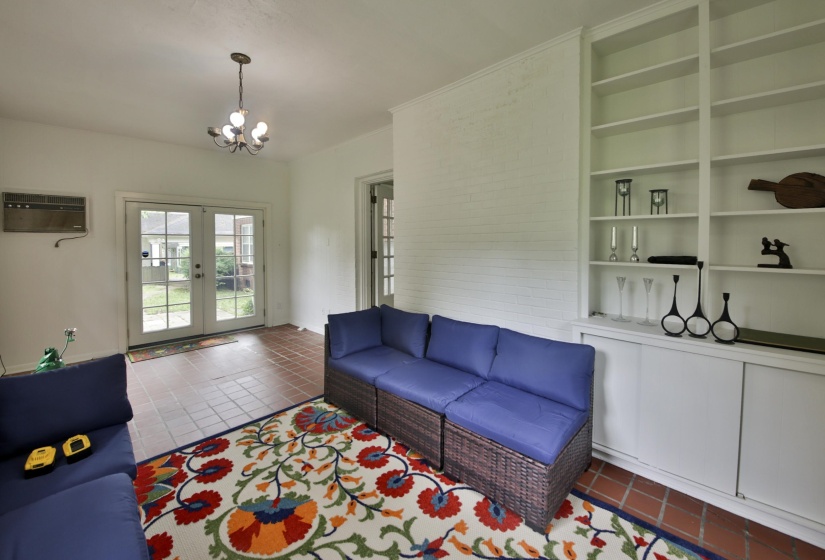 Room featuring terracotta tile flooring, built-in shelving, white cabinetry, a flush-mount light fixture, and French doors