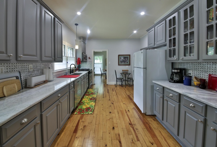 Galley kitchen featuring hardwood flooring, light gray cabinetry, light-toned countertops, and recessed lighting