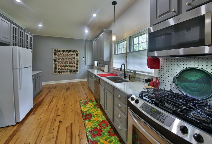 Spacious kitchen featuring wood-finish flooring, light grey cabinetry, white countertops, and stainless steel appliances