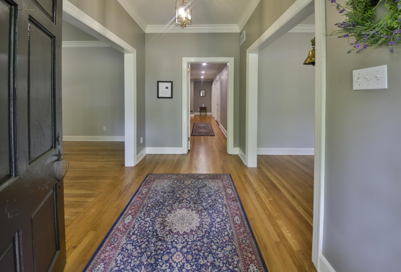 Entryway featuring wood-finish flooring, white baseboards, and crown molding