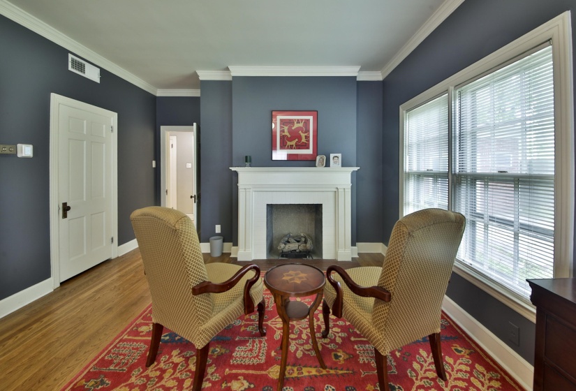 Fireplace featuring a white mantel, wood-finish flooring, white crown molding, white baseboards, and a paneled white door