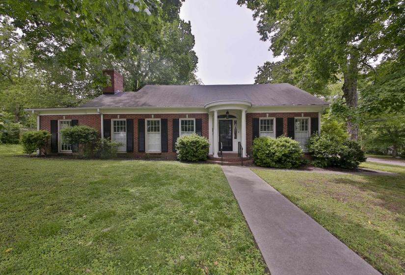 Traditional brick exterior featuring a covered portico with white columns, black front door, and a walkway