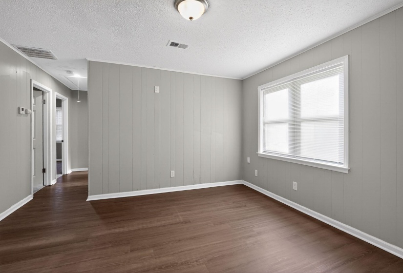 Spacious room featuring wood-finish flooring, light gray vertical paneling, and white trim