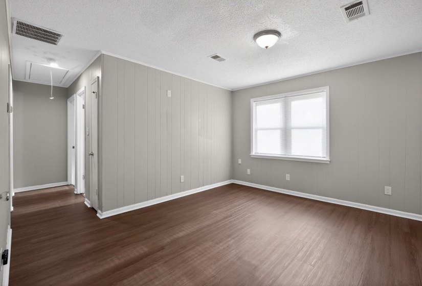 Spacious room featuring wood-finish flooring and light gray paneling