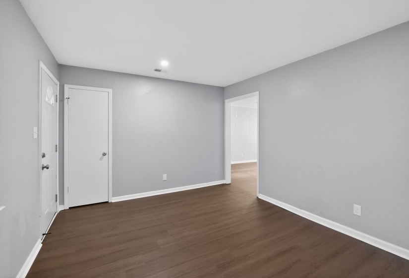 Spacious interior featuring wood-finish flooring, light gray walls, white trim, recessed lighting, and white doors with chrome hardware