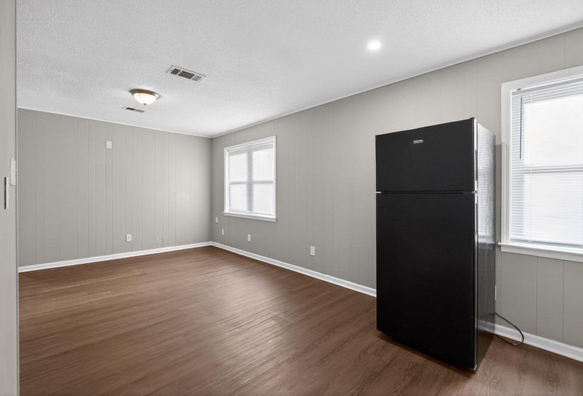 Interior room featuring wood-finish flooring, light gray vertical plank walls, and white trim