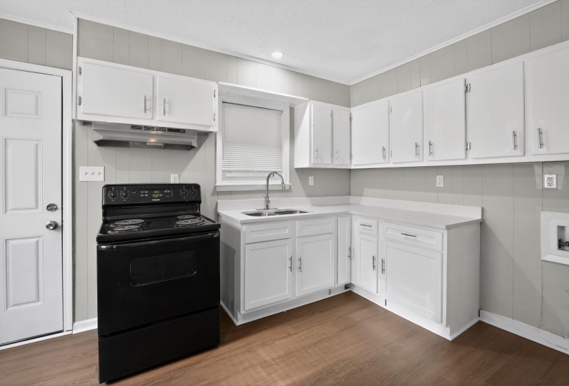 Kitchen featuring white cabinetry, light countertops, and a black freestanding electric range