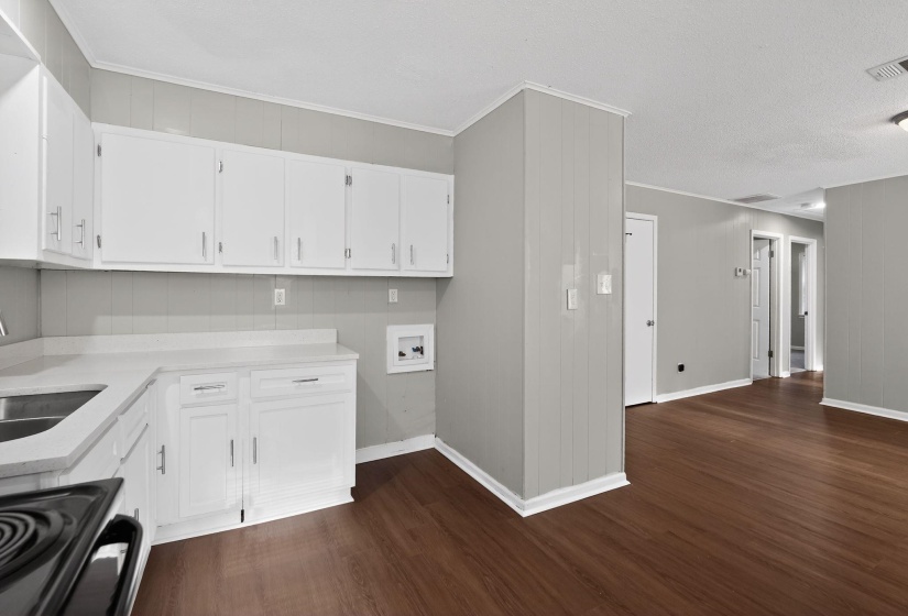 Kitchen area featuring white cabinetry, light countertops, a stainless steel sink, and wood-finish flooring