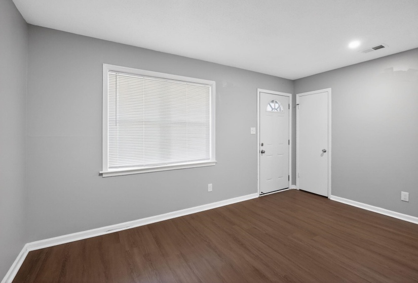 Spacious room featuring wood-finish flooring, light gray walls, and white baseboards