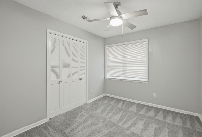 Bedroom featuring light gray walls, gray patterned carpet, and a ceiling fan with integrated lighting