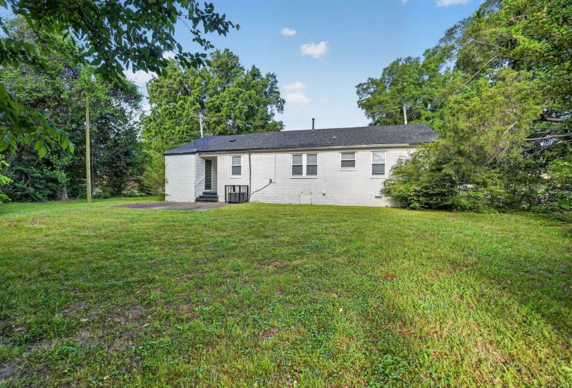 Expansive backyard featuring a large grass area and mature perimeter trees