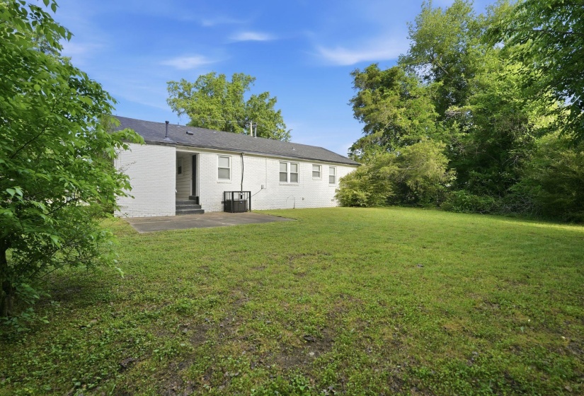 Expansive green lawn with mature trees bordering the property