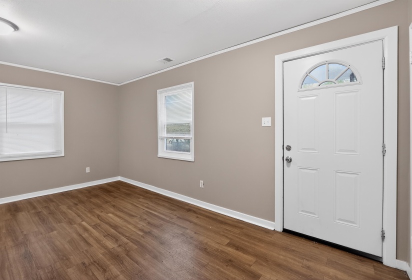 Entry area featuring a paneled door with an arched transom, wood-finish flooring, neutral wall paint, and white trim