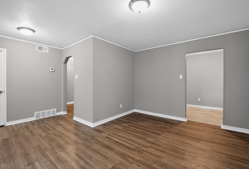 Spacious room featuring wood-finish flooring, neutral gray wall paint, and white trim