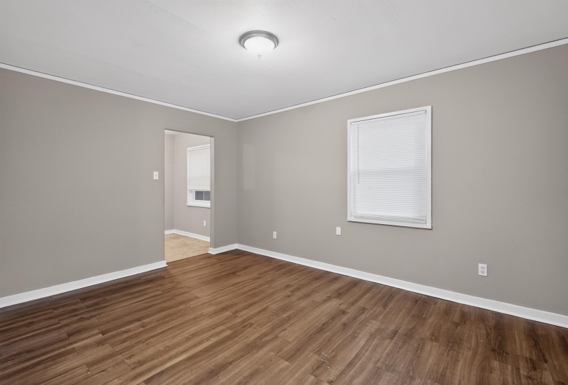 Spacious interior room featuring wood-finish flooring, light gray walls, and white trim