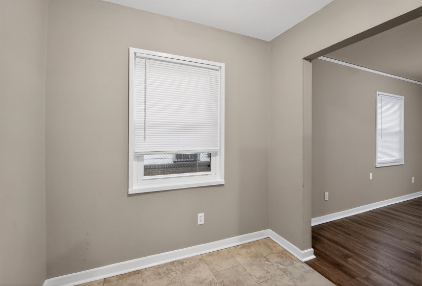 Neutral-toned walls with white trim, featuring a window with white blinds and an electrical outlet