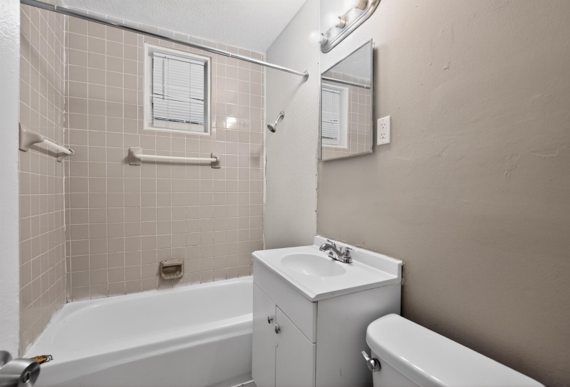 Full bathroom featuring a tub/shower combination with beige square tiling and a window with blinds