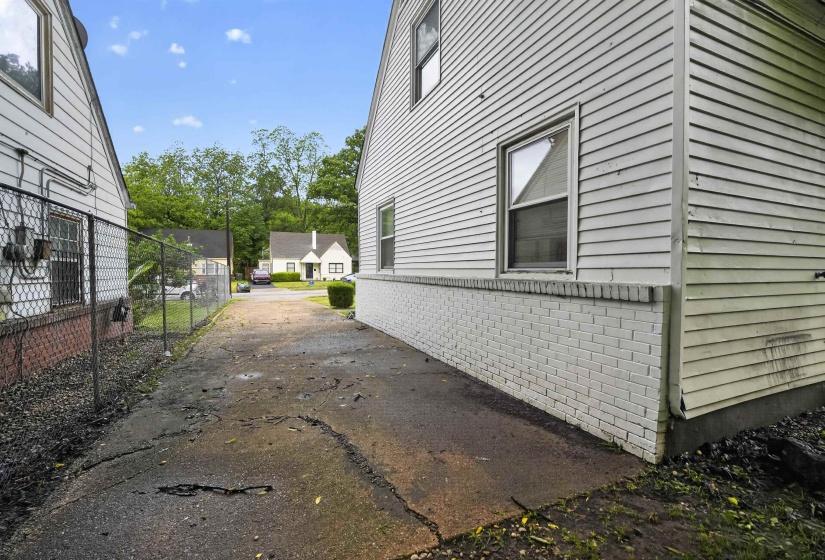 White horizontal siding exterior with a painted brick foundation and a single-pane window