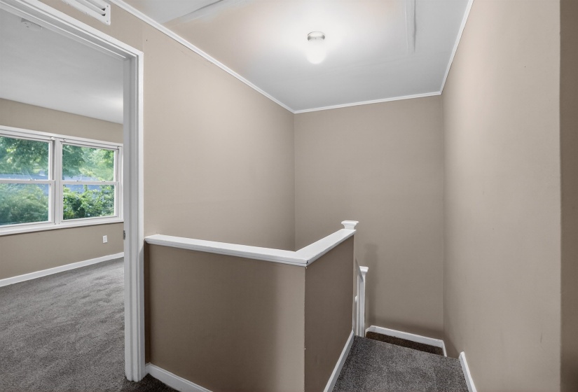 Interior landing with carpeted stairs and white railing
