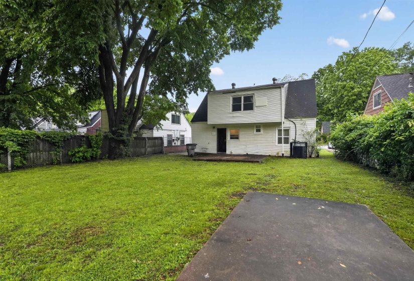 Expansive green lawn with mature trees and a partially visible wooden deck