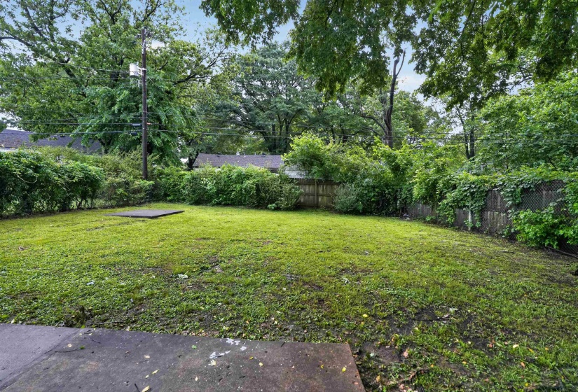 Expansive grass lawn bordered by mature trees and established fencing