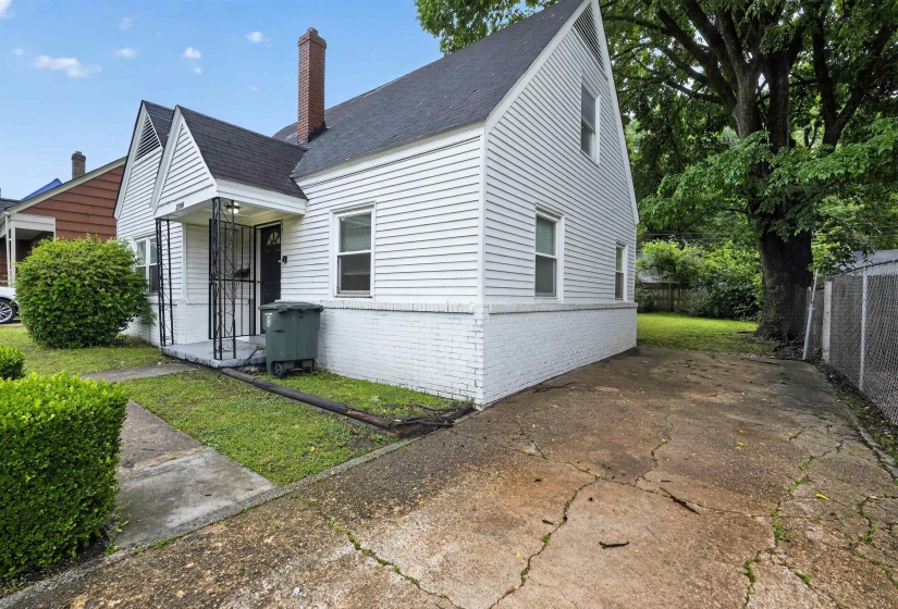 White siding exterior with a brick foundation, featuring a covered front entry with wrought iron supports