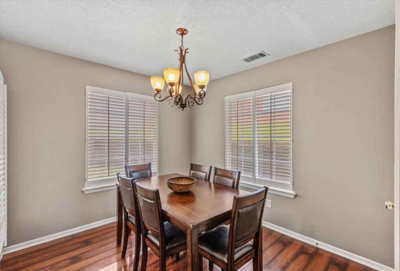 Dedicated dining area featuring wood-finish flooring, neutral wall tones, and a decorative chandelier