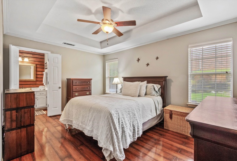 Bedroom with wood-finish flooring, tray ceiling, and ceiling fan with integrated lighting