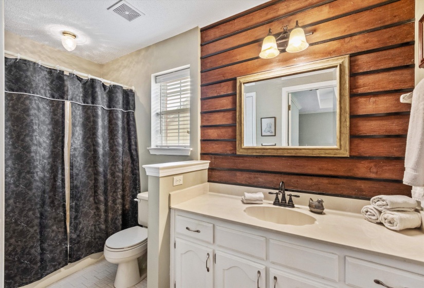 Bathroom featuring a single vanity with extensive cabinet storage, a light-colored countertop, and a built-in sink