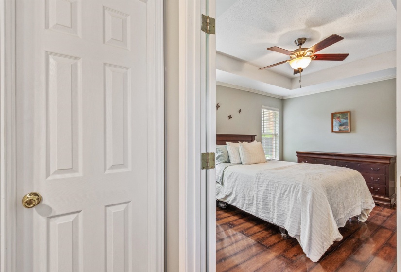Bedroom featuring wood-finish flooring, a tray ceiling, and a ceiling fan with integrated lighting