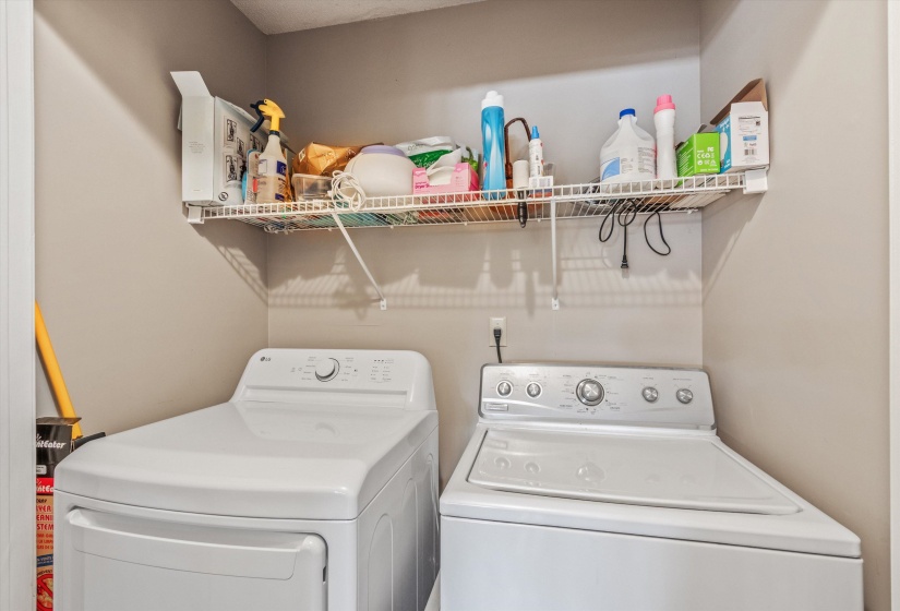 Dedicated laundry area featuring a white top-load washing machine, a white front-load dryer, and an overhead wire shelving unit