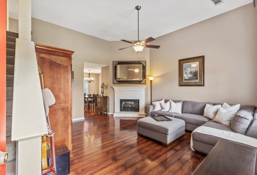 Living area featuring wood-finish flooring, a vaulted ceiling, and a ceiling fan with integrated lighting