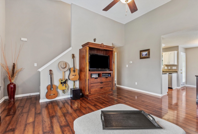 Vaulted ceiling with a ceiling fan, wood-finish flooring, and light gray wall paint