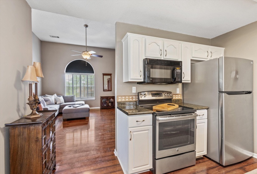 Kitchen featuring white cabinetry, stainless steel appliances, granite-style countertops, and a decorative tile backsplash