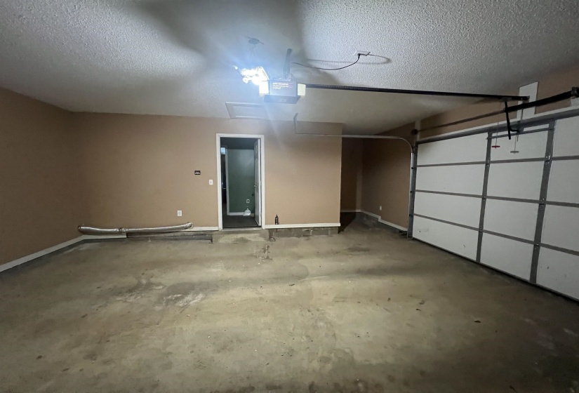 Attached garage featuring a panel-style door, concrete flooring, and an interior access door