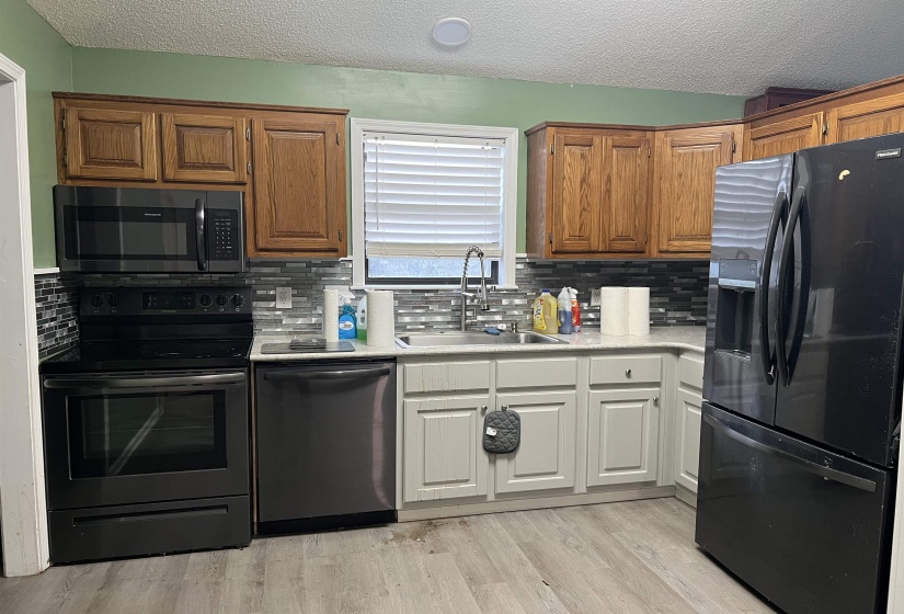 Kitchen featuring wood-finish upper cabinetry, light-toned lower cabinetry, and a subway tile backsplash