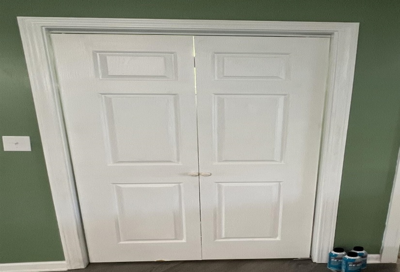 White paneled bi-fold doors framed by decorative trim work