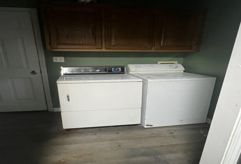 Laundry area featuring overhead cabinetry, a white paneled door, and vinyl plank