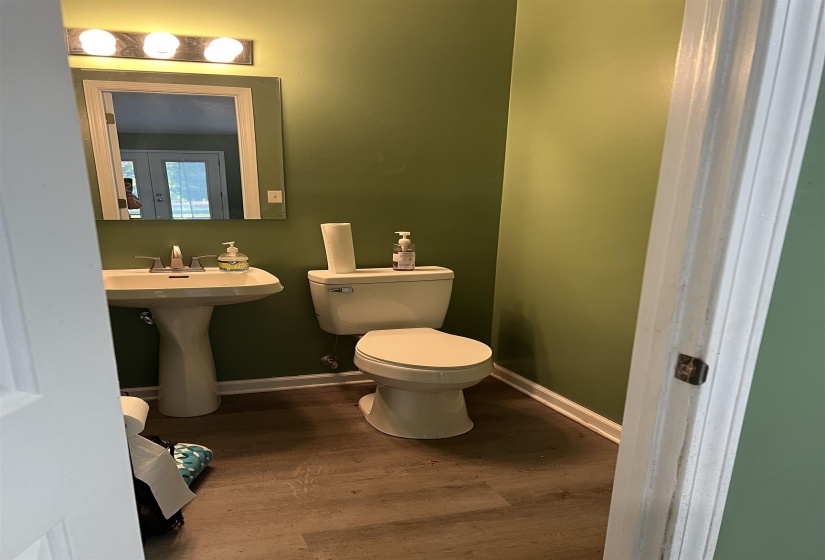 Pedestal sink and commode in a powder room with vinyl plank