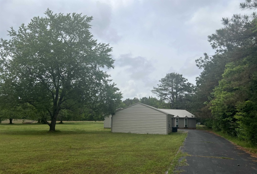 Expansive green lawn with mature trees and a paved driveway leading to the residence