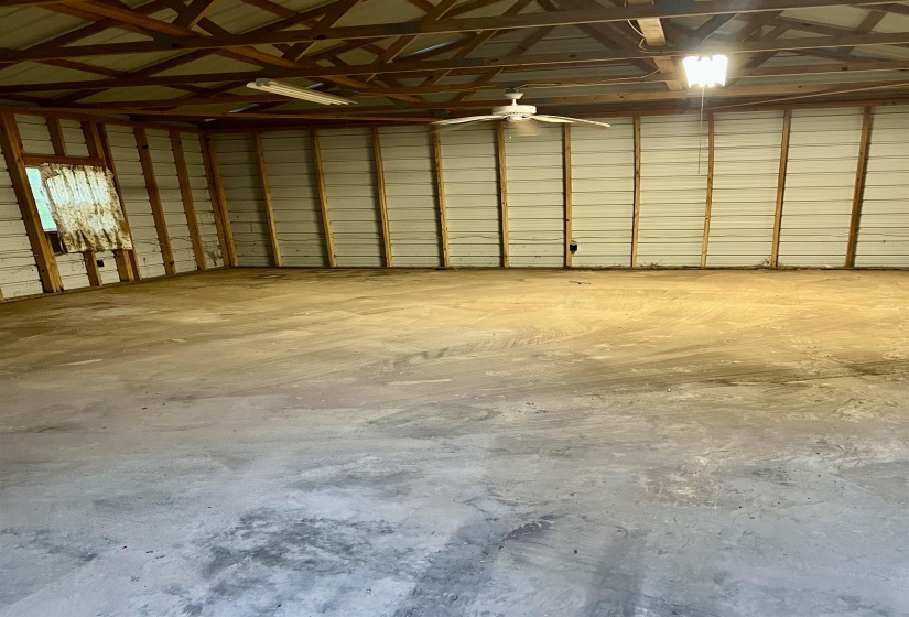 Spacious interior featuring a concrete floor, exposed wood ceiling beams, and corrugated metal wall panels