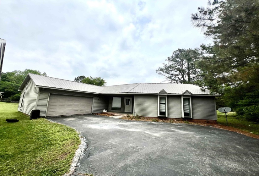 Exterior residence with light gray horizontal siding, an attached garage, and a metal roof