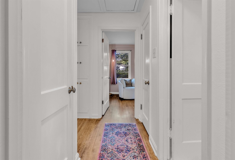 Hallway featuring wood-finish flooring, white paneled doors, and built-in cabinetry