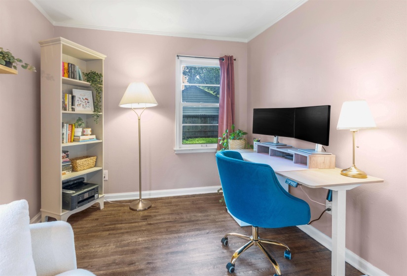 Room featuring wood-finish flooring, a white built-in bookcase, and a window with white trim