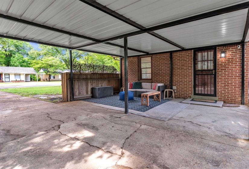 Covered patio area featuring brick exterior walls and a security screen door